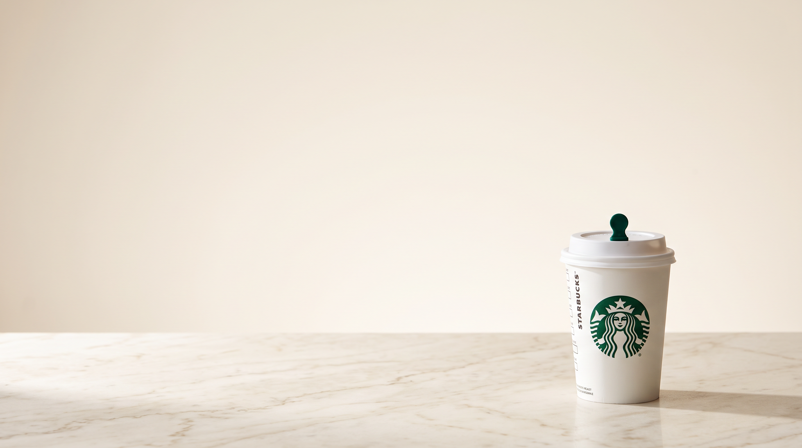 Kelímek Starbucks se zeleným logem sirény na světlém mramoru