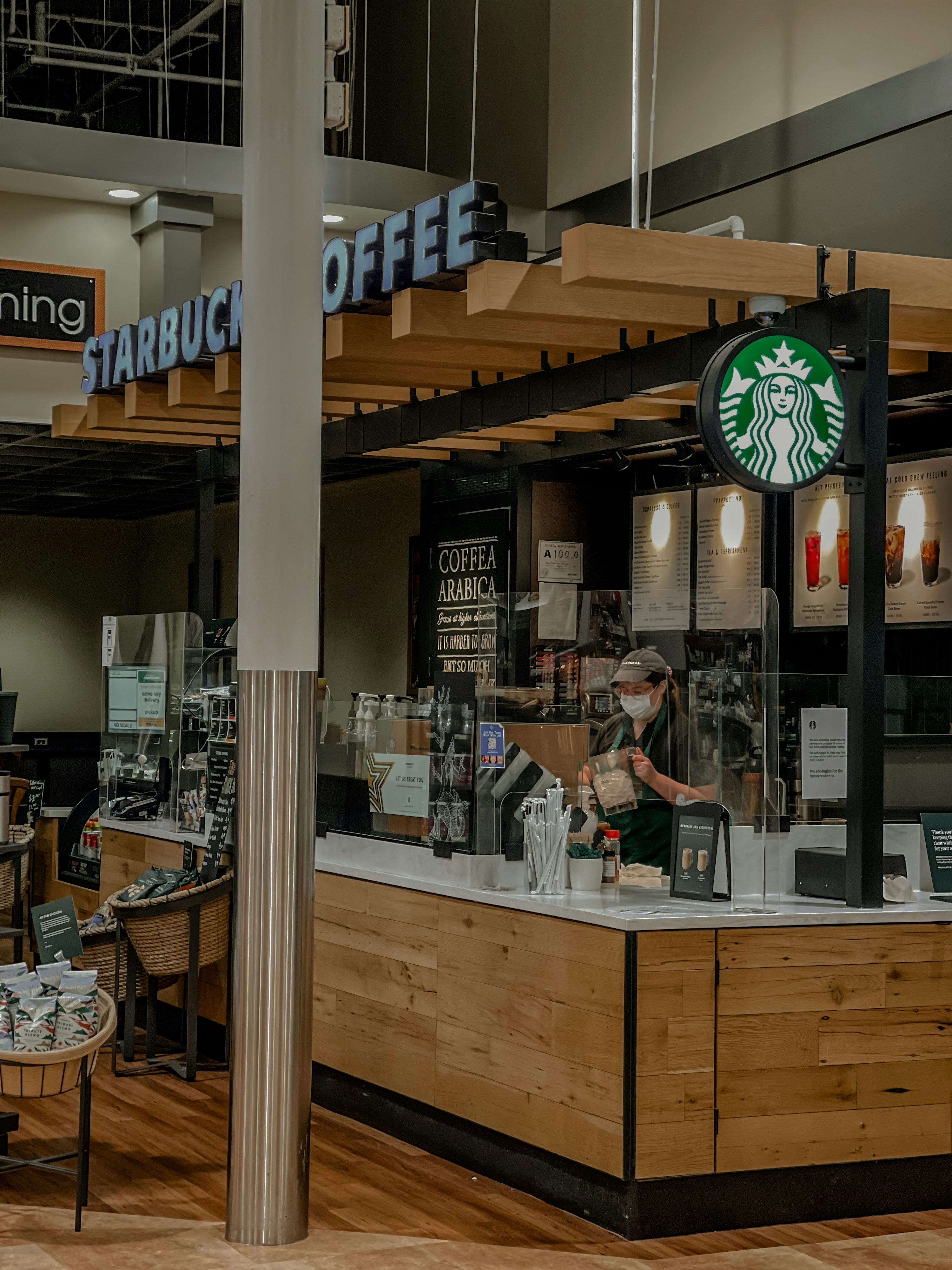 Prodejna Starbucks s logem zelené sirény a baristou